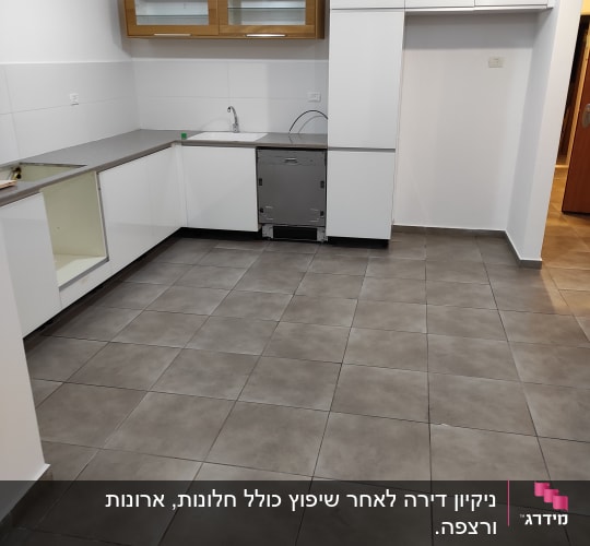 מטבח ריק עם רצפה נקייה וארונות לבנים